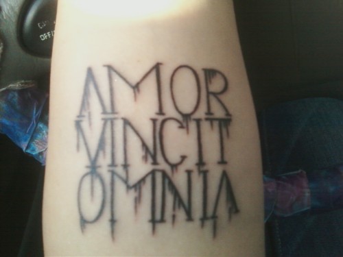 It says “Amor Vincit Omnia,” meaning love conquers all.